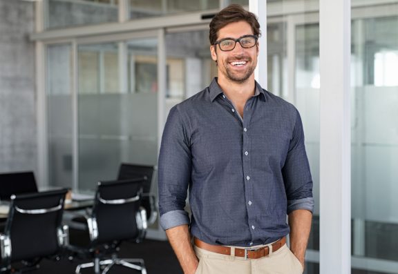 Professional man wearing glasses smiling with hands in pocket