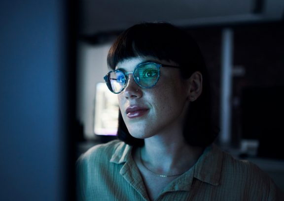 Woman with glasses working at computer in a dark office