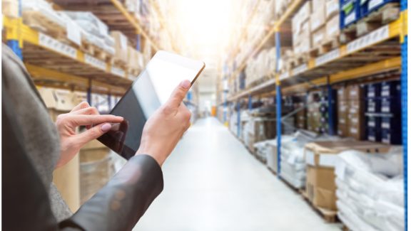 Hands holding tablet in warehouse