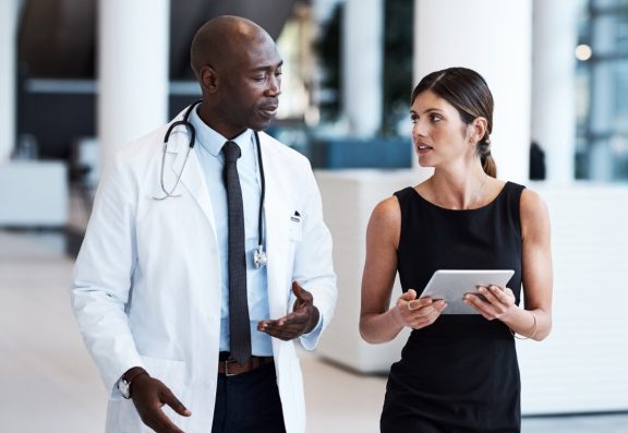 Male doctor reviewing information on a table held by female colleague