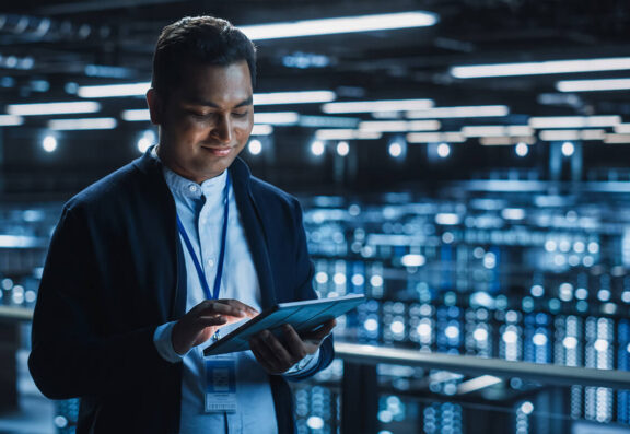Professional man in IT environment smiling at a tablet